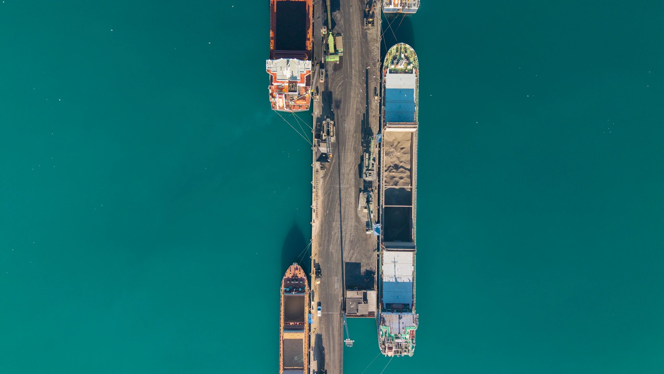 Aerial view of cargo ships docked at a port loading and unloading materials