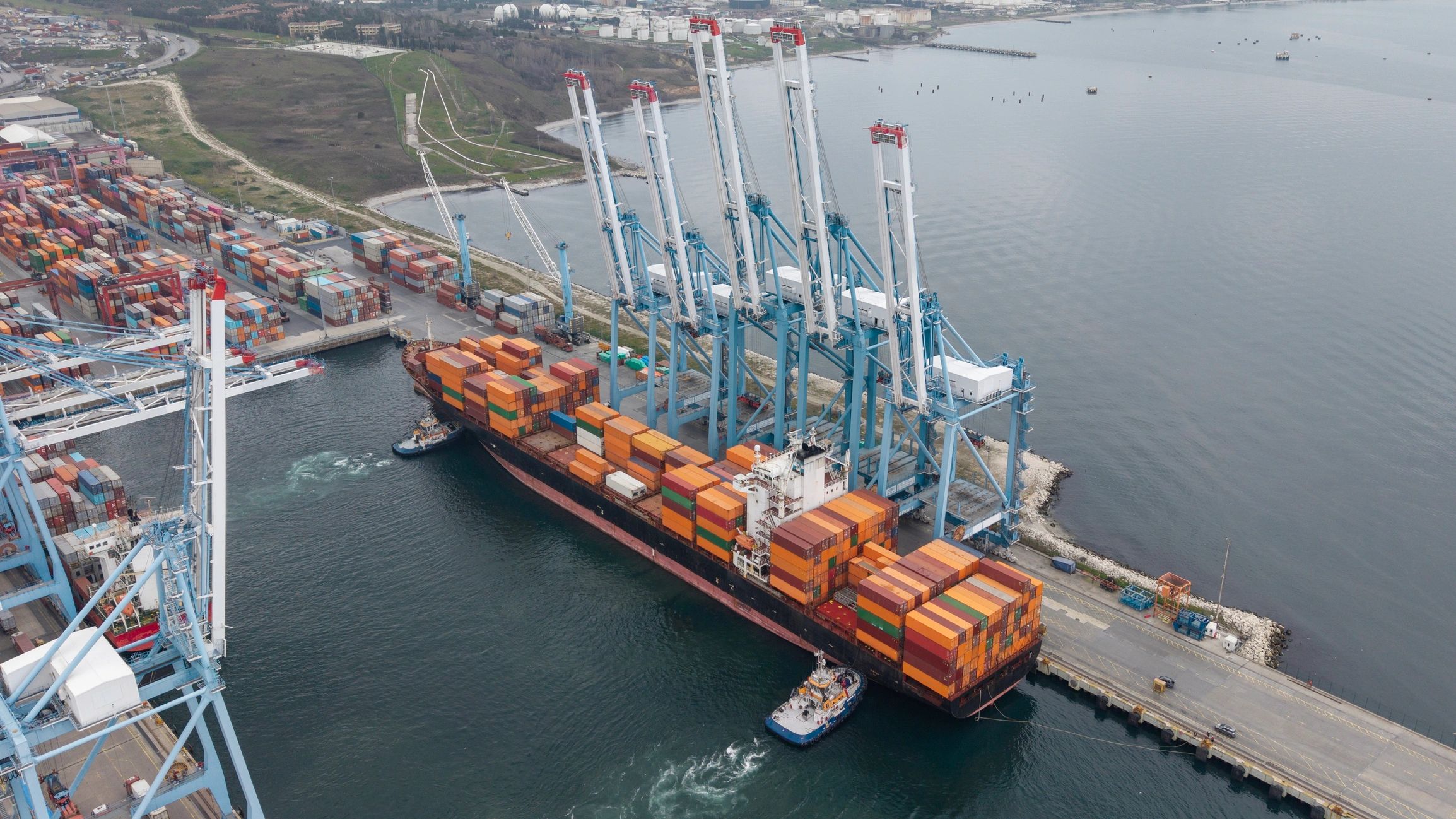 Container ship docking at industrial port with gantry cranes